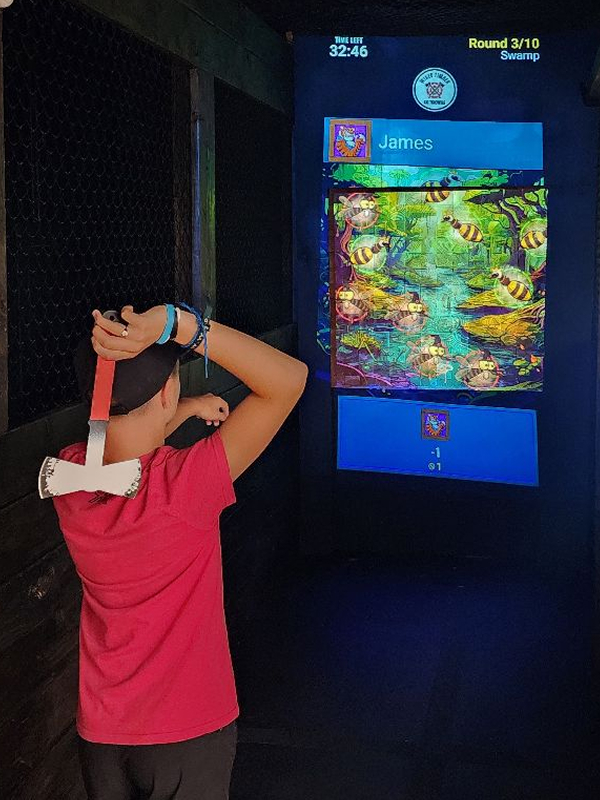 Teen playing axe throwing game.