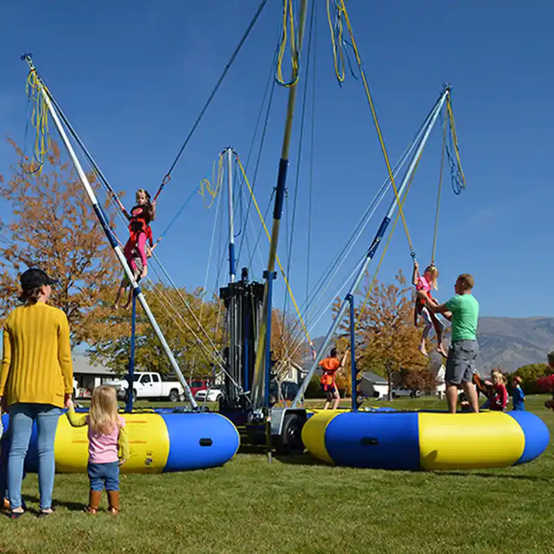 Family enjoying bungee trampoline attraction in Hurricane Utah near Zion National Park with kids jumping and flipping in harness