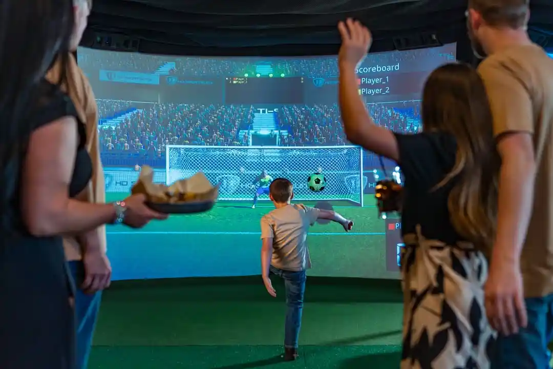 Family playing indoor soccer simulator game in Hurricane Utah near Zion National Park inside HD sports simulator room for groups and kids