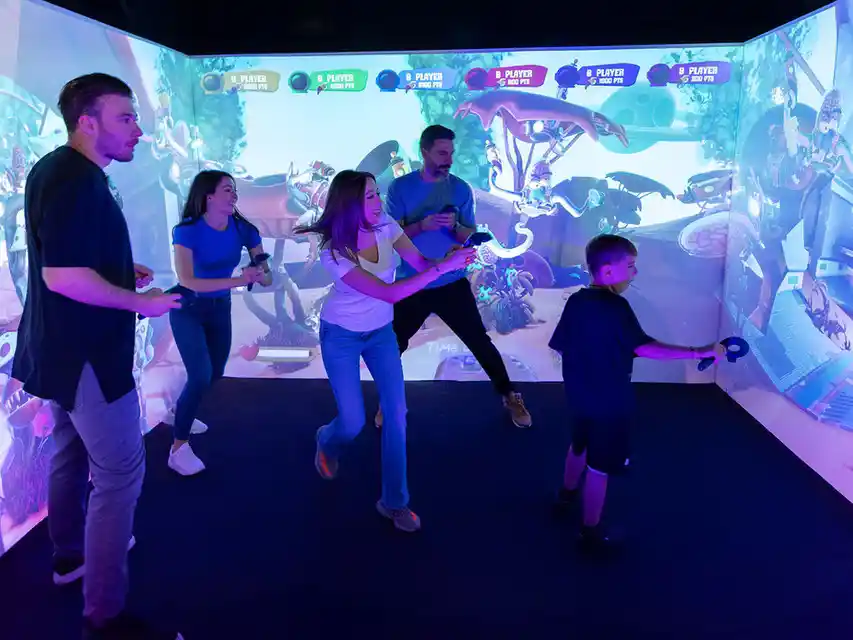 qbix-interactive-game-room-hurricane-utah-group-vr-arena Group playing QBIX interactive game room in Hurricane Utah with 270 degree immersive screens and multiplayer VR experience