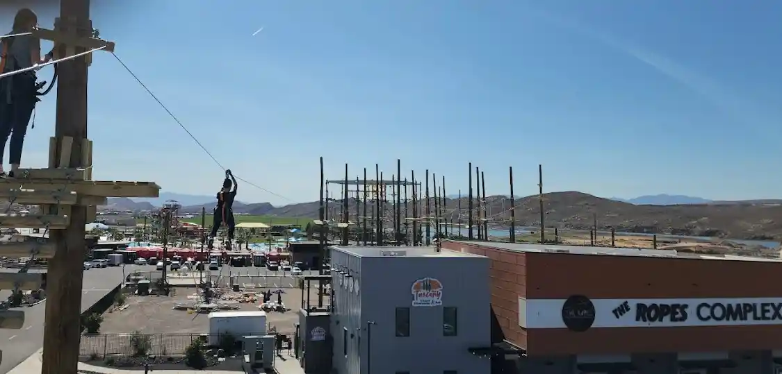 Zipline rider soaring across course above adventure park in Hurricane Utah near Zion National Park during daytime experience